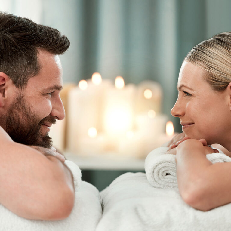 Uomo e donna che si sorridono su lettini da massaggi